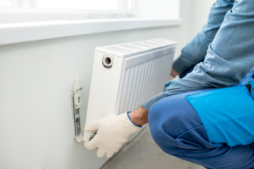 Workman,Mounting,Water,Heating,Radiator,On,The,White,Wall,Indoors,